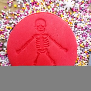 May include: A red circle with a skeleton imprint. The circle is surrounded by colorful sprinkles.