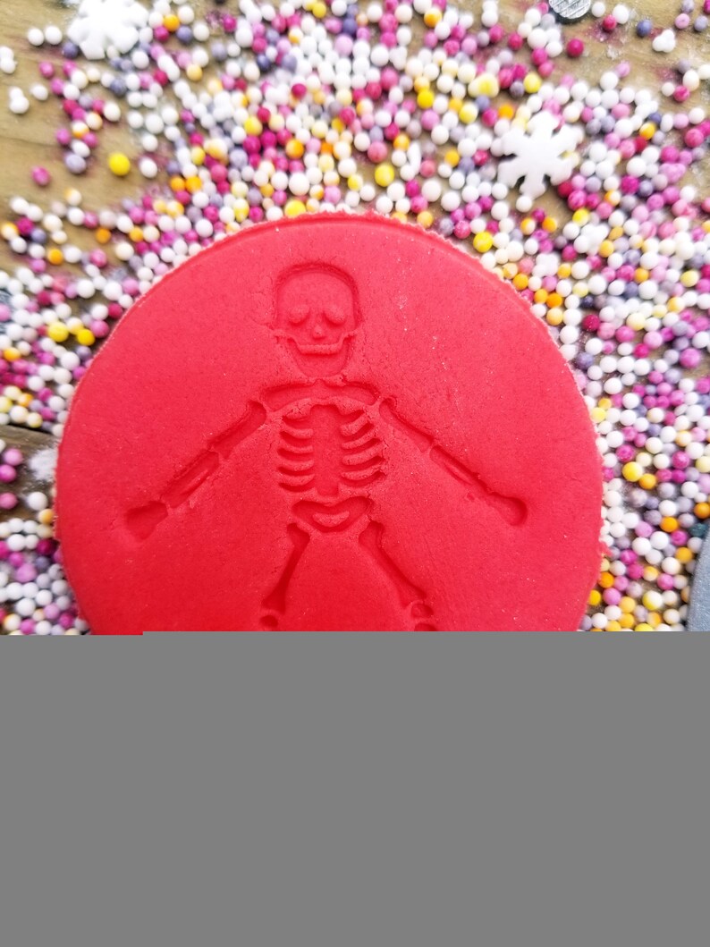 May include: A red circle with a skeleton imprint. The circle is surrounded by colorful sprinkles.