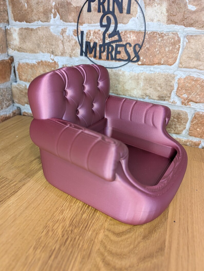 May include: A mauve-colored miniature sofa with a tufted back and rolled arms. The small decorative chair is made of a smooth material and has a classic design. The words "PRINT 2 IMPRESS" are in the background.