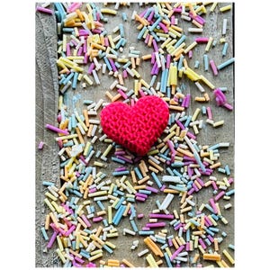 May include: A red heart-shaped candy sprinkles on a wooden surface with colorful sprinkles.