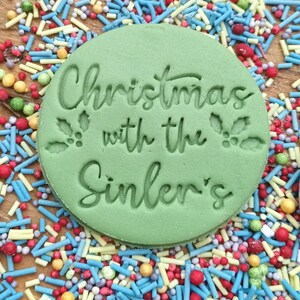 May include: Green round cookie cutter with the text "Christmas with the Sinler's" and a holly leaf design.