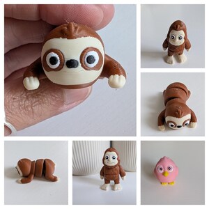 May include: A collection of small, 3D-printed animal figurines. The set includes a brown and cream-colored sloth, a brown Bigfoot-like figure, and a pink bird with yellow beak. The sloth is shown in multiple poses. The figurines are on a white surface.