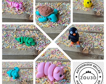 May include: A collection of colorful, handmade polymer clay animal figurines, including an axolotl, turtle, alligator, penguin, chick, caterpillar, and a pig. The figurines are set on a wooden surface covered in colorful sprinkles.
