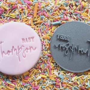May include: Two round, pink and gray, cookie cutters with the text "BABY Thompson" and "Yaaassss Mom" in white.