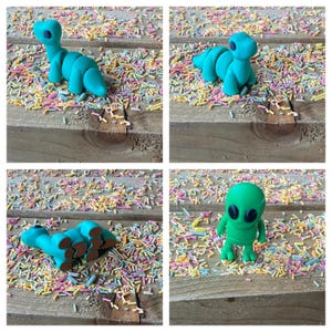 May include: Four green plastic toys on a wooden surface covered in colorful sprinkles. The toys are a dinosaur, a segmented worm, a dinosaur with its tail curled, and an alien.