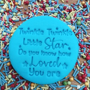 May include: A blue silicone stamp with the text "Twinkle Twinkle Little Star Do you know how Loved you are" in white lettering. The stamp is surrounded by colorful sprinkles.
