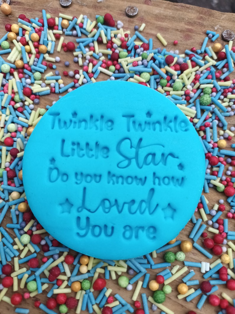 May include: A blue silicone stamp with the text "Twinkle Twinkle Little Star Do you know how Loved you are" in white lettering. The stamp is surrounded by colorful sprinkles.
