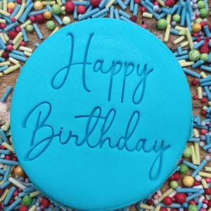 May include: A blue round cake topper with the words "Happy Birthday" in white script.