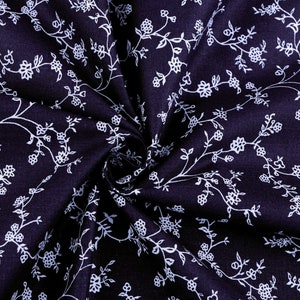 Könnte beinhalten: Ein dunkelblauer Stoff mit einem weißen Blumenmuster. Der Stoff ist gefaltet und verdreht, wodurch ein wirbelnder Effekt entsteht.