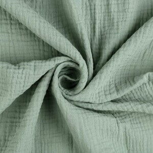 Könnte beinhalten: Nahaufnahme eines salbeigrünen Stoffes mit strukturierter, zerknitterter Optik. Das Material ist gefaltet und gewirbelt, wodurch in der Mitte ein Spiraleffekt entsteht. Das Gewebe des Stoffes ist sichtbar, was auf ein leichtes, atmungsaktives Textil hindeutet.