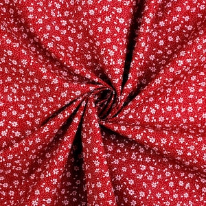 Könnte beinhalten: Roter Stoff mit einem weißen Blumenmuster. Der Stoff ist gefaltet und verdreht, wodurch ein wirbelnder Effekt entsteht.