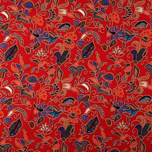 Könnte beinhalten: Roter Stoff mit einem sich wiederholenden Muster aus blauen, orangen und weißen Blumenmotiven. Der Stoff hat einen dezenten Schimmer.