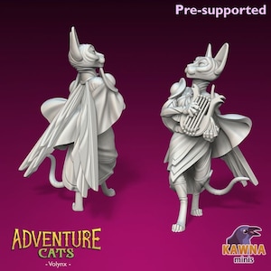 May include: Two 3D printed miniature figurines of cats dressed as fantasy characters. The cat on the left is wearing a cloak and the cat on the right is playing a harp. The text "Adventure Cats - Volyxn -" is at the bottom of the image.
