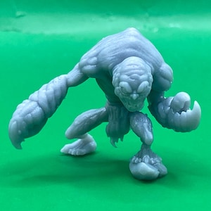 May include: A gray, monster figurine with a textured surface. The creature has a large head, claw-like hands, and a hunched posture. The figurine is a detailed representation of a fantasy or sci-fi character.