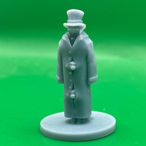 May include: A grey 3D printed miniature figurine of a person wearing a top hat and a long coat. The figurine is standing on a round base.