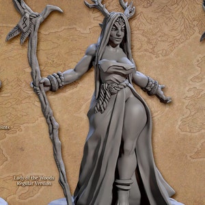 May include: A grey, detailed miniature figurine of a female dryad with antlers, holding a staff. The figurine is standing on a round base with a textured surface. The text "HOLDA - LADY OF THE WOODS" is visible at the top of the image.