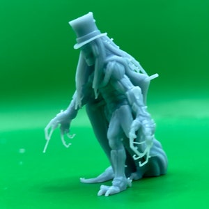 May include: A gray 3D printed figurine of a skeletal figure wearing a top hat and a long coat. The figure has long, bony fingers and appears to be in a walking pose.