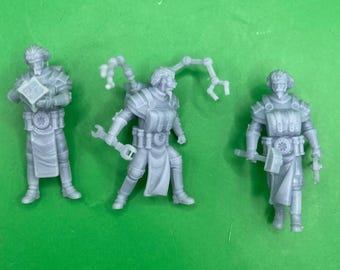 May include: Three gray 3D printed miniature figures of people wearing futuristic clothing and holding tools. The figures are posed in different stances and have detailed features.