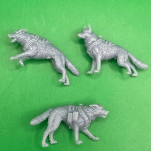 May include: Three gray plastic toy dogs wearing harnesses. The dogs are in different poses, with one standing, one running, and one jumping.