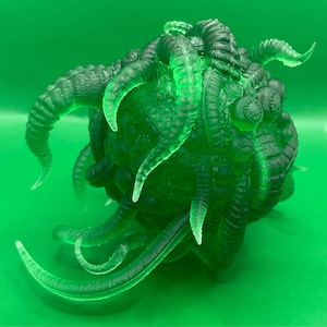 Könnte beinhalten: Eine grün durchscheinende, 3D-gedruckte Skulptur einer Kreatur mit mehreren Tentakeln und Augen. Die Kreatur scheint ein groteskes, außerirdisches Wesen zu sein.