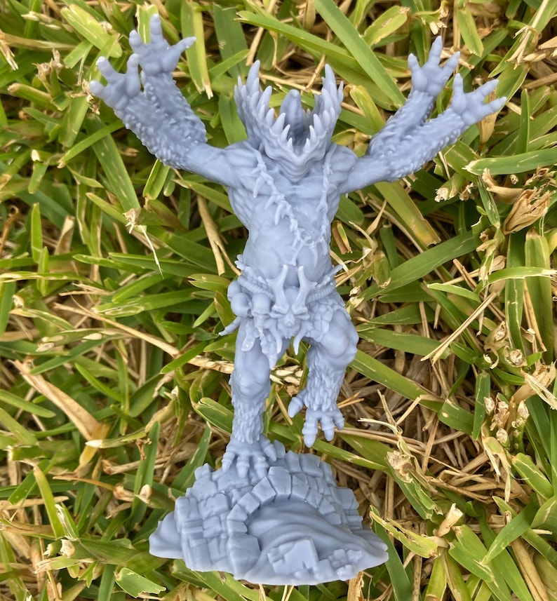 May include: A grey 3D printed miniature of a monstrous creature with sharp teeth and claws, standing on a rocky base.