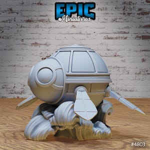 May include: A grey 3D printed model of a futuristic spaceship with a dome-shaped top and two wings. The spaceship is sitting on a base that resembles waves. The model is labelled "EPIC Miniatures #4803".
