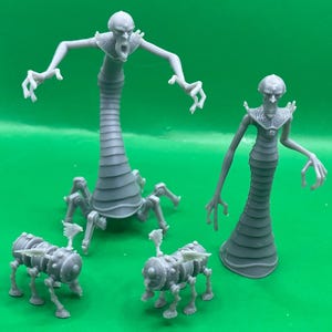 Könnte beinhalten: Eine Sammlung grauer, 3D-gedruckter Fantasy-Kreaturen. Die Figuren umfassen zwei große, humanoide Figuren mit länglichen Körpern und ausgestreckten Armen sowie zwei kleinere, mechanisch aussehende Kreaturen mit mehreren Beinen und flügelartigen Strukturen.
