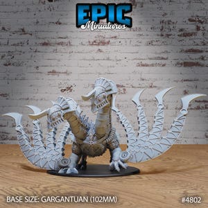 May include: A detailed, grey miniature dragon with mechanical elements, including gears and articulated wings. The dragon is posed on a black base. The text "EPIC Miniatures" is visible at the top. Base size: Gargantuan (10.2 cm).