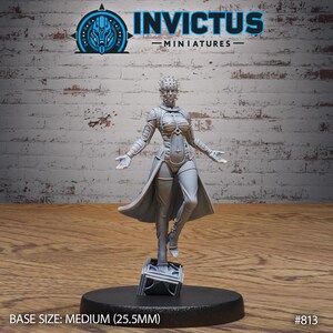 May include: A gray, detailed miniature figure of a woman with a spiky crown and a long, flowing robe. The figure is standing on a square base with a textured surface. The base is 25.5 mm in diameter. The miniature is part of the Invictus Miniatures collection.