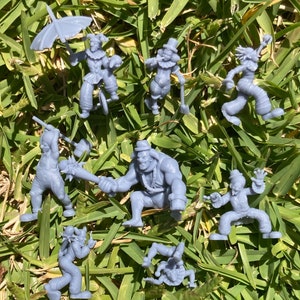 Könnte beinhalten: Ein Set aus acht grauen Plastikfiguren, die Clowns darstellen. Die Figuren sind in verschiedenen Posen dargestellt, darunter Jonglieren, Trompetespielen und Schaufeln halten. Die Figuren sind vor einem Hintergrund aus grünem Gras platziert.