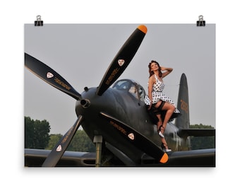 May include: A woman in a white and black polka dot dress sits on the wing of a black and green airplane. The airplane has a large propeller and the words "NO STEP" written on the side.