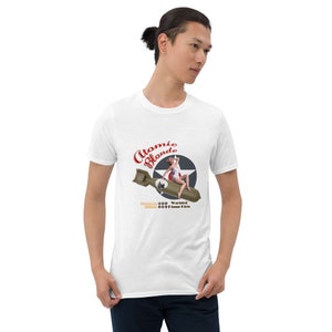 May include: White t-shirt with a graphic of a pin-up girl sitting on a bomb with the text "Atomic Blonde" and "Warbird Pin-up Girls".