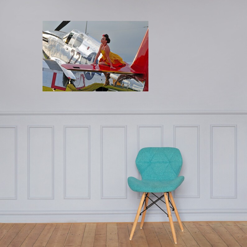 May include: A woman in a yellow dress sits on the wing of a silver and red airplane. The airplane has the number "224" on the side.