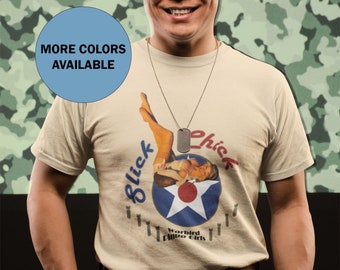 May include: A beige t-shirt with a graphic of a woman in a pin-up pose with the text "Blick Chick" and "Warbird Pin-up Girls".