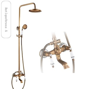 May include: Antique brass shower fixture with a round showerhead and handheld sprayer. The fixture has a vintage design with white porcelain handles and decorative accents. The text "Antiquebrass A" is visible on the left side.