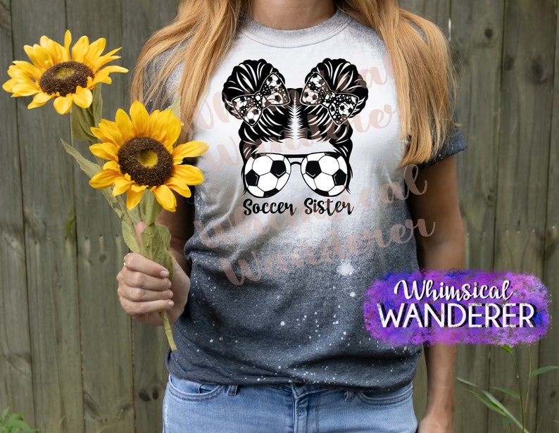 May include: A black and white graphic design of a girl with a soccer ball and sunglasses. The text "Soccer Sister" is below the graphic. The graphic is on a gray and white tie-dye t-shirt.