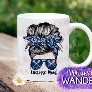 May include: White ceramic mug with a graphic of a woman with a messy bun wearing a blue and white bandana with lacrosse sticks printed on it. The bandana is tied around her bun. She is wearing sunglasses with lacrosse sticks printed on the lenses. The text "Lacrosse Mom" is printed below the graphic.