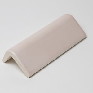 May include: A white ceramic corner tile with a rounded edge.