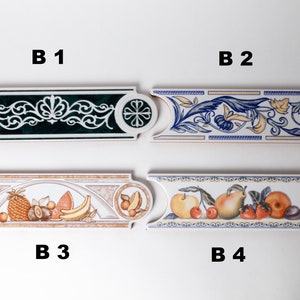 May include: Four ceramic tile border designs with different patterns. The first tile has a green background with a white floral design. The second tile has a white background with a blue and yellow floral design. The third tile has a white background with a brown and orange fruit design. The fourth tile has a white background with a yellow and orange fruit design.