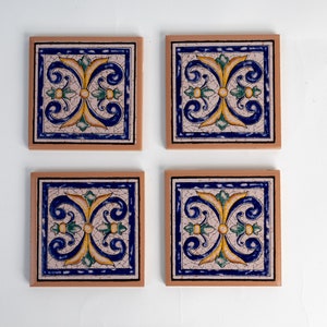 May include: Set of four square ceramic coasters with a blue, yellow, and green floral design on a white background. The coasters have a light brown border.