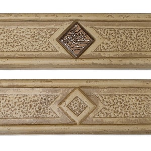 May include: Two beige ceramic tile moldings with a diamond-shaped design. The top molding has a brown diamond with a textured surface. The bottom molding has a plain beige diamond.