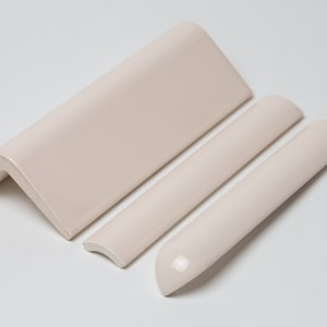 May include: Three ceramic tile trim pieces in a light cream color. The pieces are a corner trim, a half-round trim, and a quarter-round trim.