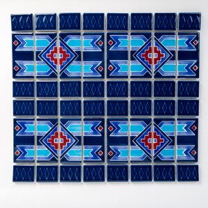 Puede incluir: Una hoja de mosaico azul y blanco con un patr&oacute;n geom&eacute;trico en rojo y azul. El patr&oacute;n presenta una forma de diamante con una cruz en su interior y una serie de l&iacute;neas horizontales.