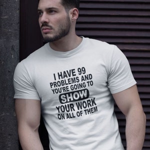 Op de afbeelding: Wit T-shirt met zwarte tekst die luidt: "Ik heb 99 problemen en je gaat je werk op alle laten zien".