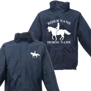 May include: Navy blue equestrian jacket featuring a white horse and rider silhouette. The jacket has a high collar and a zip closure. The text "RIDER NAME" and "HORSE NAME" is printed on the back of the jacket.