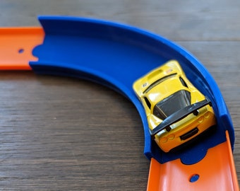 May include: A yellow toy car with a black spoiler races around a blue and orange plastic track.