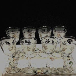May include: Set of eight clear glass stemmed drinking glasses with a silver and black leaf design.