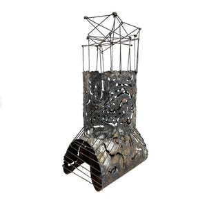 May include: A black metal sculpture with a geometric design. The sculpture is made of welded metal and has a rough, textured surface.