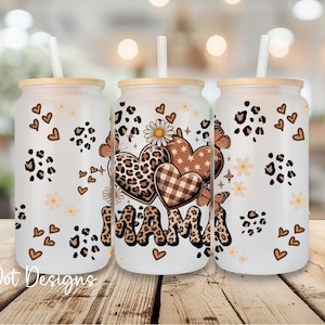 May include: Three glass tumblers with lids and straws. The tumblers feature a white background with leopard print spots, hearts, butterflies, and the word "MAMA" in a leopard print font. The tumblers are decorated with a floral design.