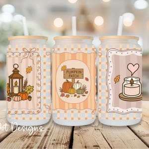 May include: Three glass tumblers with lids and straws, each featuring a fall-themed design. One tumbler has a lantern and pumpkins, another reads "Pumpkin Patch," and the third has a candle and heart. The tumblers are decorated with autumn colors.